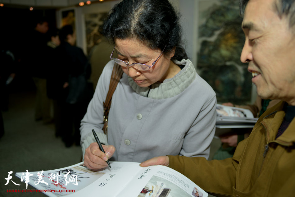 “春之恋”津门女书画家精品展3月9日在天津人民美术出版社展厅展出，图为张永敬为观众签名留念。