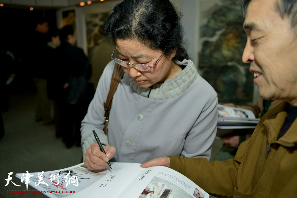 “春之恋”津门女书画家精品展3月9日在天津人民美术出版社展厅展出，图为张永敬为观众签名留念。