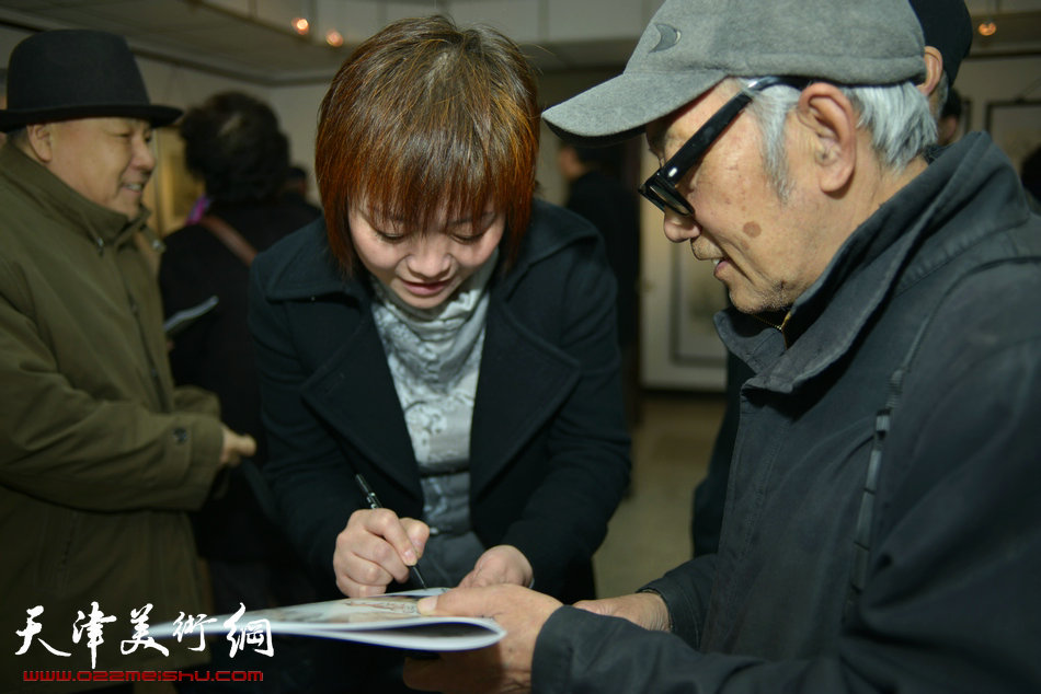 “春之恋”津门女书画家精品展3月9日在天津人民美术出版社展厅展出，图为张永敬为观众签名留念。