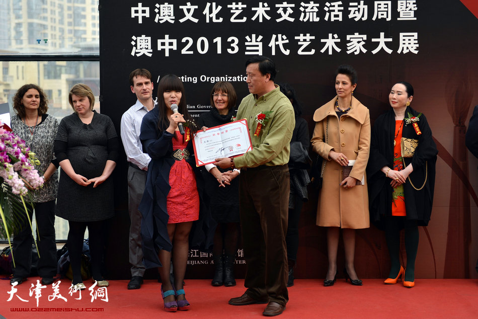 天津市梅江国际艺术馆馆长萧冰向旅澳华人画家关伟颁发名誉馆长证书。