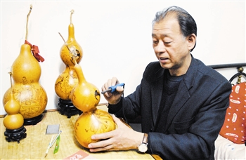 李新明在制作烙画葫芦。