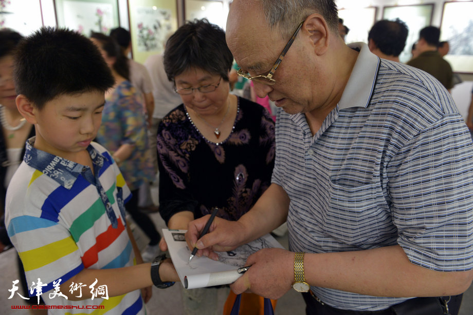 天津花鸟四家师生作品展在图书大厦书天艺苑开幕。图为史如源在画展现场为小观众签名。