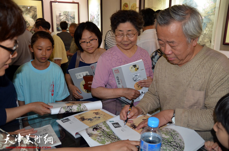 天津花鸟四家师生作品展在图书大厦书天艺苑开幕。图为阮克敏在画展现场为观众签名留念。