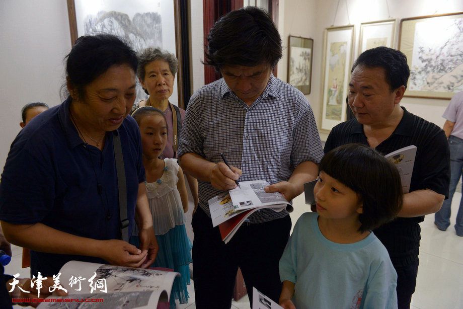 天津花鸟四家师生作品展在图书大厦书天艺苑开幕。图为著名花鸟画家翟洪涛在画展现场为小朋友签字。