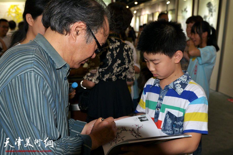 天津花鸟四家师生作品展在图书大厦书天艺苑开幕。图为郭书仁在为小朋友签名。