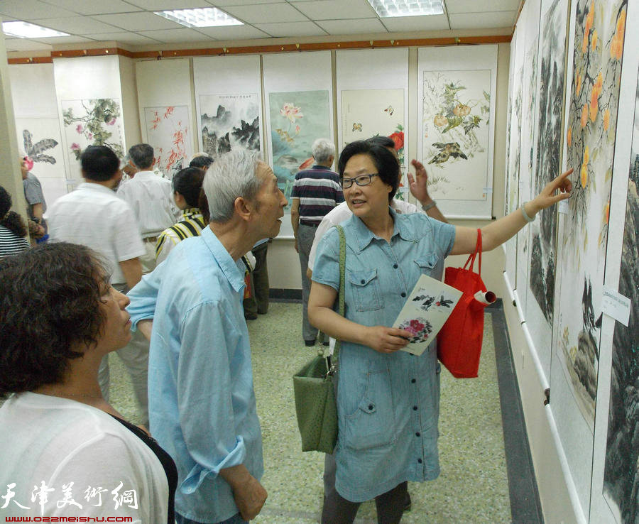 津报书画俱乐部第8届会员展揭幕。图为女画家伊汉铭给老会员点评作品