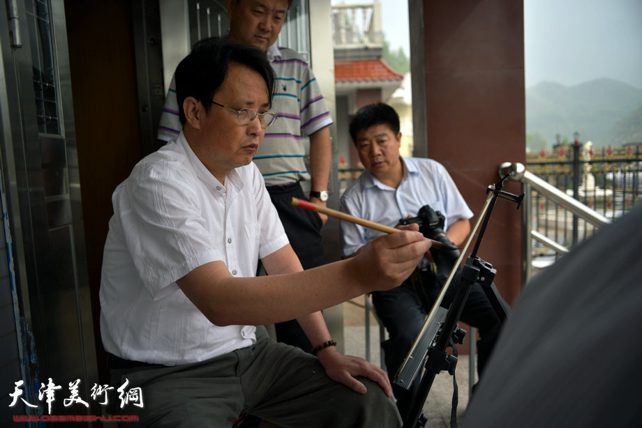 天津著名山水画家到阜平三道岭采风写生。杨永茂在画雨中太行。