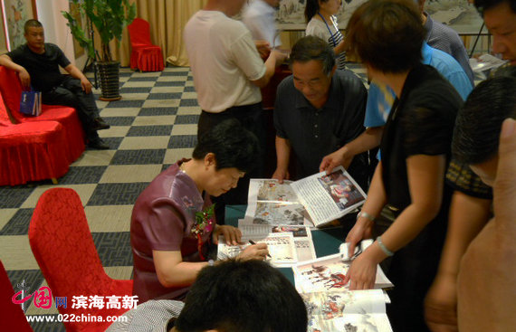 爱新觉罗·梦玉、伯骧国画精品展6月21日在宁河展出，图为梦玉在画展现场为观众签名。