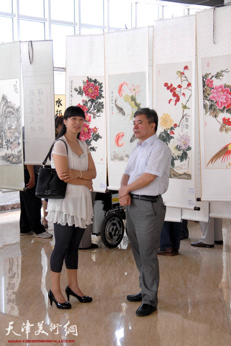 第三届“天穆杯”书画摄影展在天穆东苑开展。图为天穆村党委副书记刘玉森与回族女画家乔美娟在展览现场。