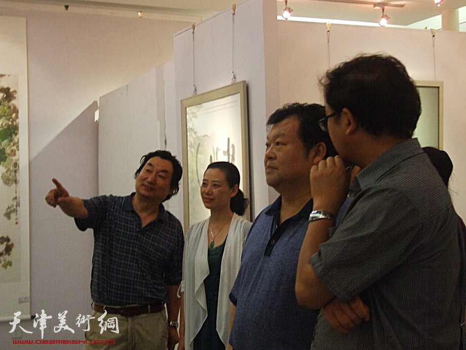 天津市委常委散襄军7月4日参观《和·心象》书画联展，韩石在天美时代艺术空间展厅为参观者讲评自己对顿子斌作品的见解。 