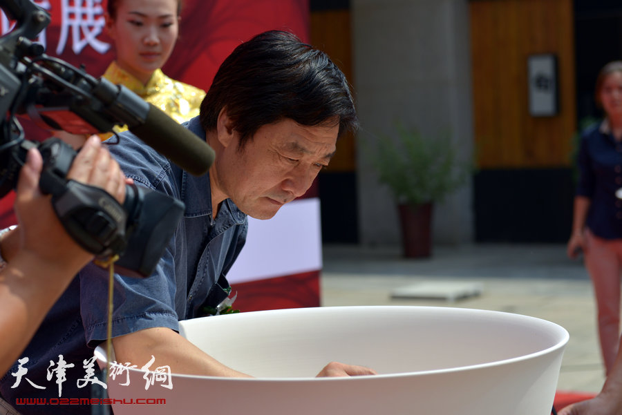 天津致园美术馆开馆仪式暨“殊涂同致—中国画名家风范展”8月24日在致园美术馆开幕，图为王宝响在聚宝盆上签名。