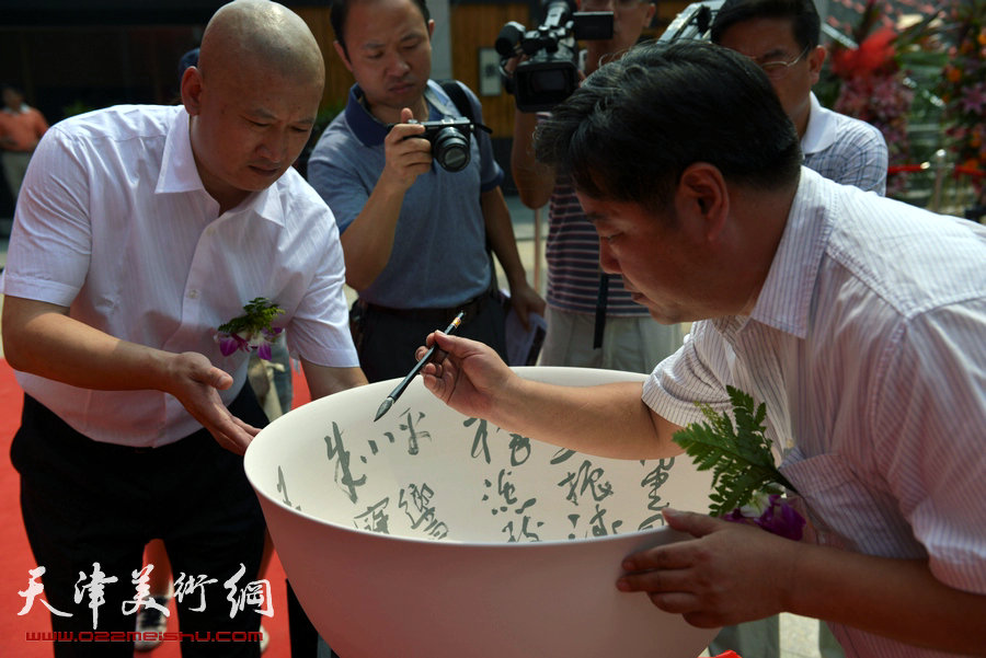 天津致园美术馆开馆仪式暨“殊涂同致—中国画名家风范展”8月24日在致园美术馆开幕，图为艺术家在聚宝盆上签名。
