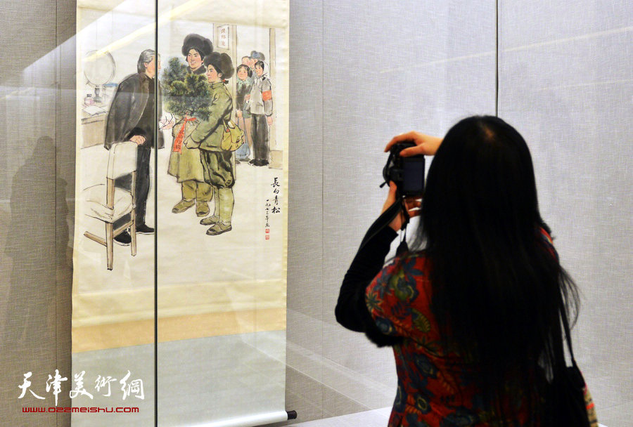 天津美术馆举办“红色经典—馆藏20世纪中国画展”，图为一观众拍周思聪中国画《长白青松》。