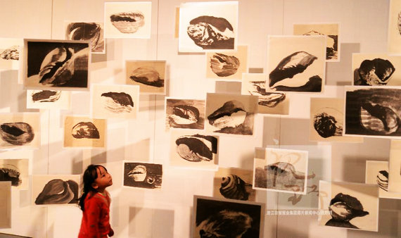 一位小女孩在观看《海螺日记》系列版画作品。