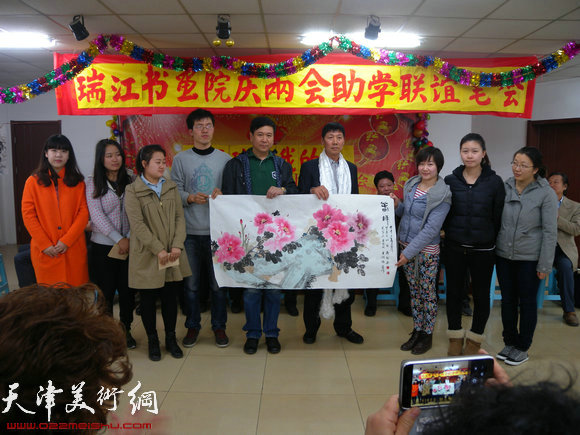 瑞江书画院举办献爱心助学助困活动，图为受助学生向企业家献画
