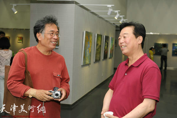 “郝跃先现代绘画系列作品展”在天津图书馆举行，图为天津文联办公室杨建国、油画家李东升在画展上交流
