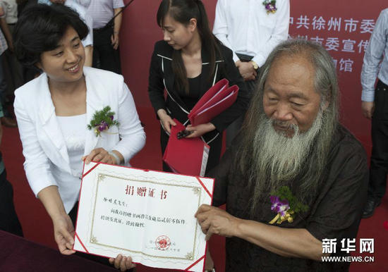 5月30日，徐培晨（右）与徐州市博物馆工作人员共同展示捐赠证书。