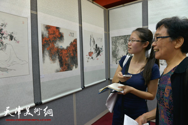 图为萧惠珠（右）在画展现场向记者介绍她的画作《憨湘云》。