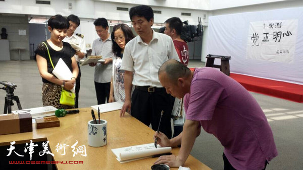 隋牟作品展6月24日在滨海新区开幕，图为隋牟在展览现场为观众签名。