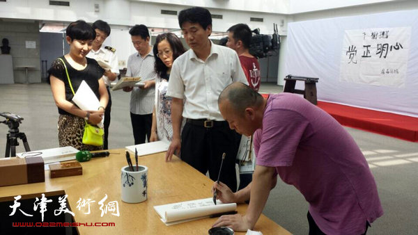 隋牟作品展6月24日在滨海新区开幕,图为隋牟在展览现场为观众签名。