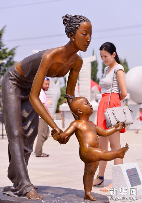参观者在中国雕塑家章华创作的雕塑《第一步》旁驻足