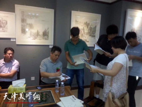 图为杨健君在画展现场为读者签名。