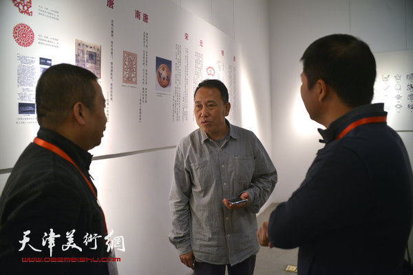 2014“西岸”剪纸艺术展现场。图为天津美术学院教授阎秉会与参展作者交谈。