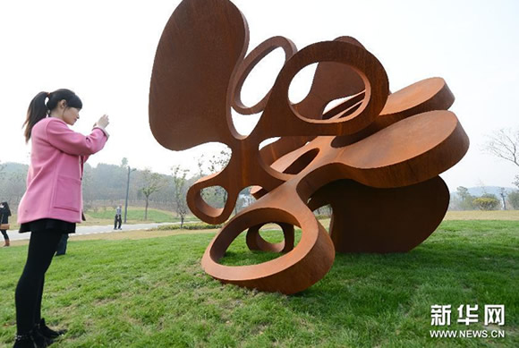 一位观众在芜湖雕塑公园内拍摄雕塑展品《作曲家》。