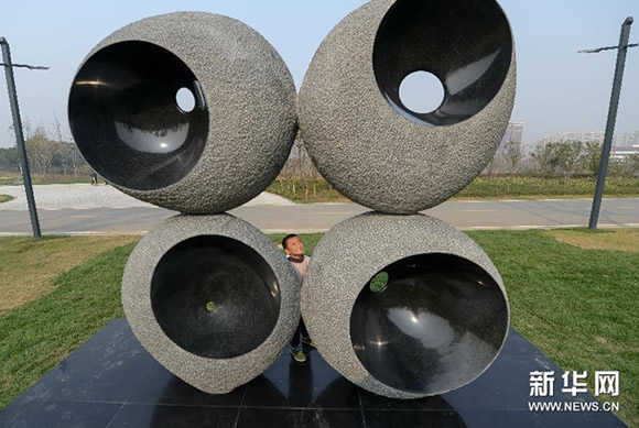 一名小朋友在芜湖雕塑公园内观看雕塑展品《四维空间》