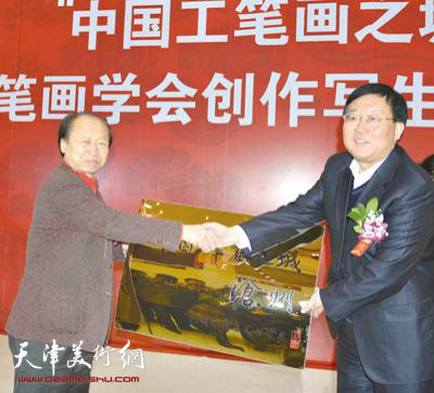 王大虎（右）从冯大中手中接过“‘中国工笔画’之城”牌匾