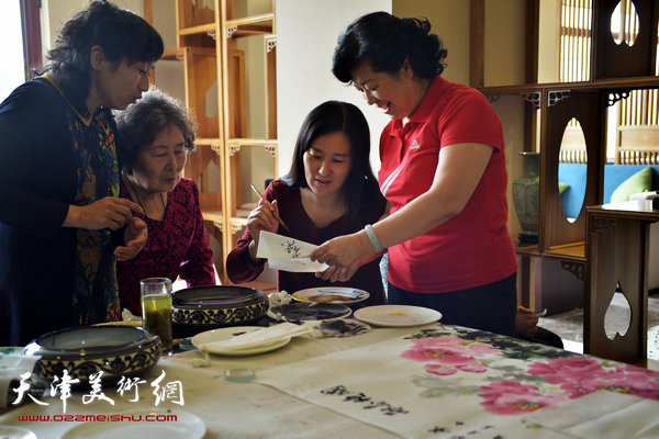 图为天津女子画院书画家募捐笔会现场，图为梦玉与部分女画家在现场。