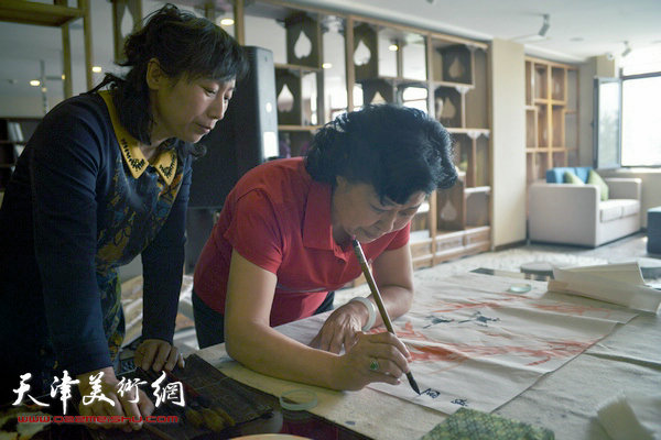 图为天津女子画院书画家募捐笔会现场，图为梦玉与张荷芝在现场。