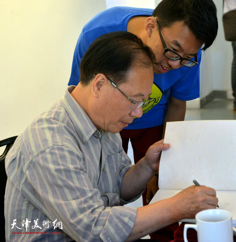 著名画家庞黎明水墨肖像画展暨作品研讨会举行，图为庞黎明为观众在《庞黎明水墨肖像集》上签字。