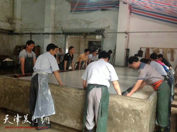 天津美协“深扎”主题活动走进泾县明星宣纸厂，图为参观学习宣纸的制作流程。