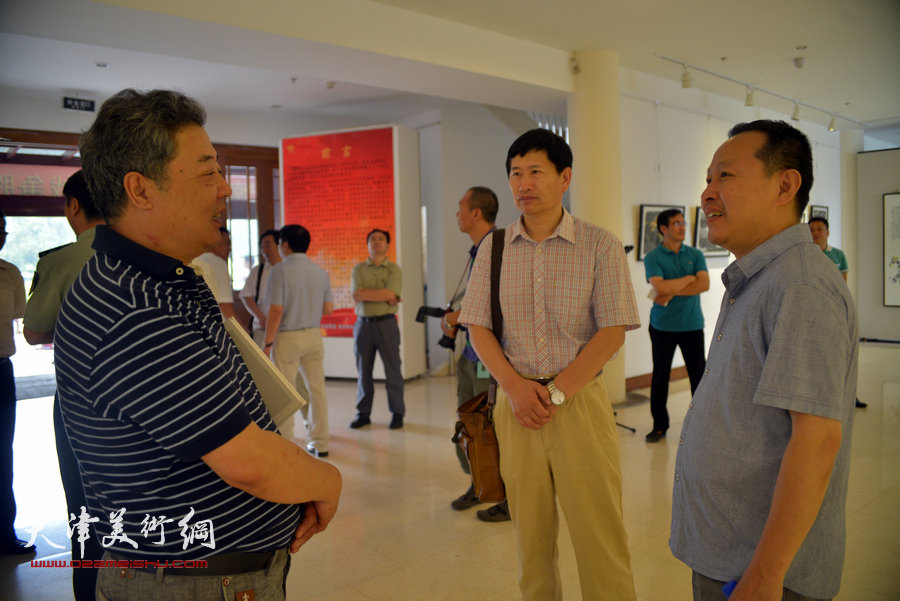 王其华、李桂金、张立涛在画展现场交谈。