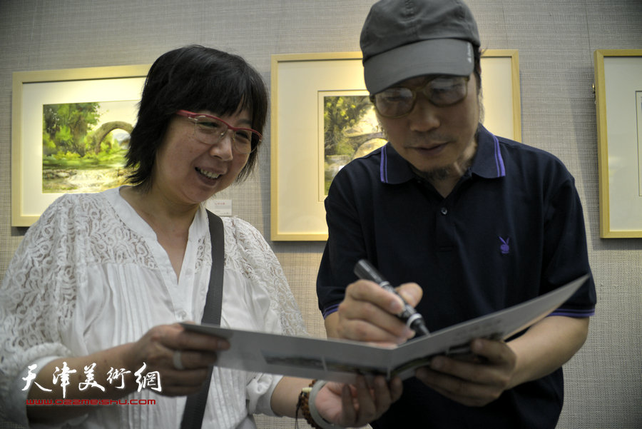 杨俊甫在水彩风景写生画展上为观众签名。