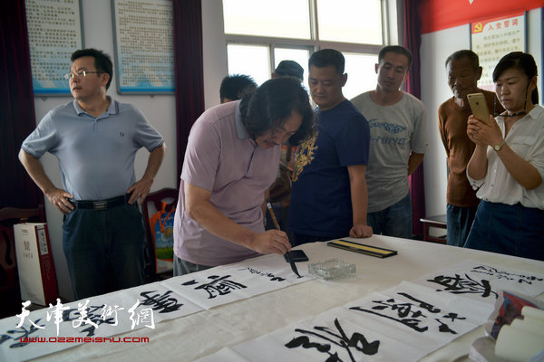 天津画院书画家为村民写横幅。图为贾广健。