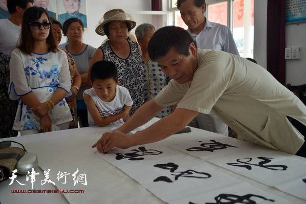 天津画院书画家为村民写横幅。图为范扬。