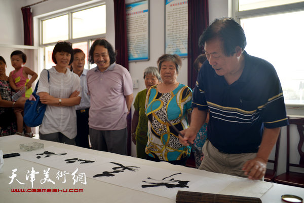 天津画院书画家为村民写横幅。图为王峰。