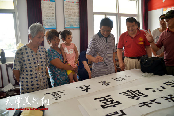 天津画院书画家为村民写横幅。图为王爱宗。