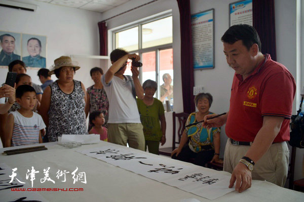 天津画院书画家为村民写横幅。图为王卫平。