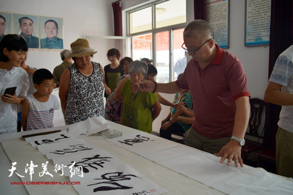 天津画院书画家为村民写横幅。图为陈嵘。