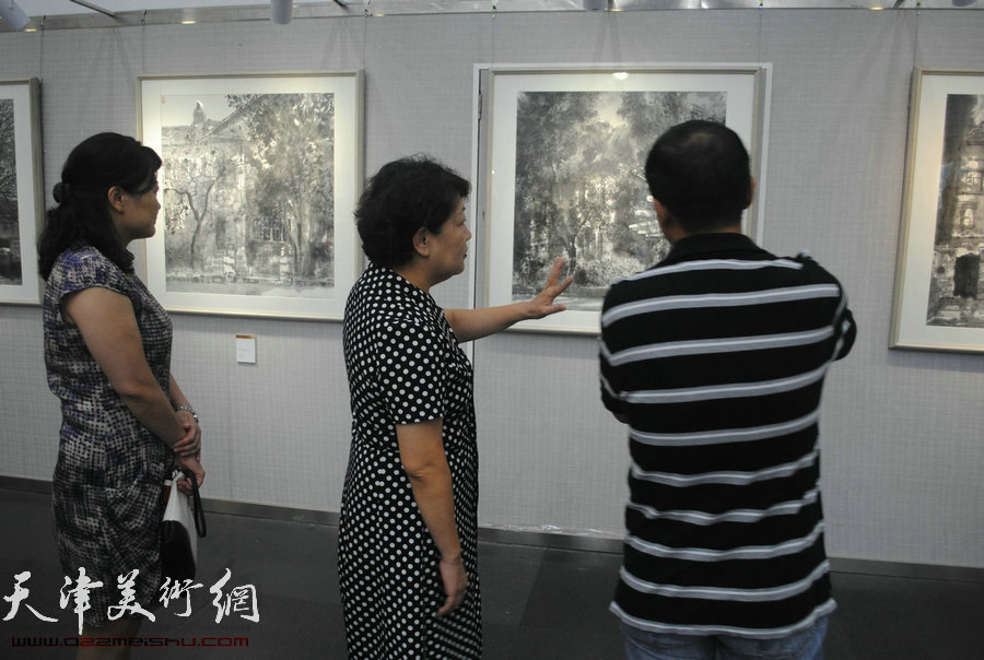 图为张俊芳在观赏作品并同魏瑞江交流。