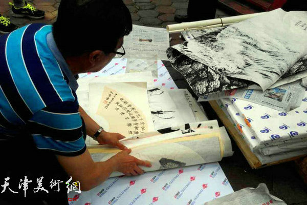 图为画家孙云川帮助俱乐部整理义捐作品。