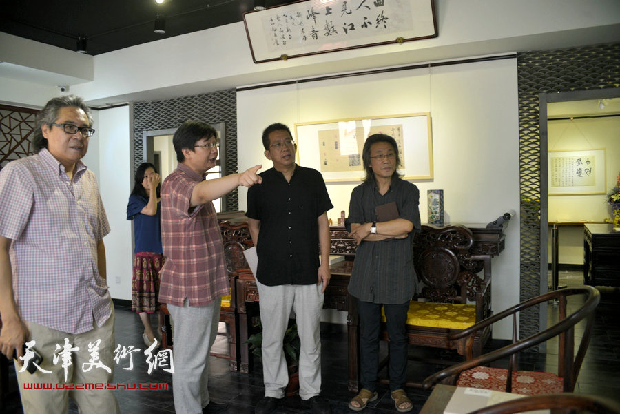 图为李毅峰、赵均、李军在观看胡健作品。