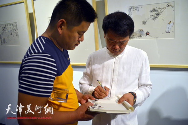 田耘在展览现场为观众签名。