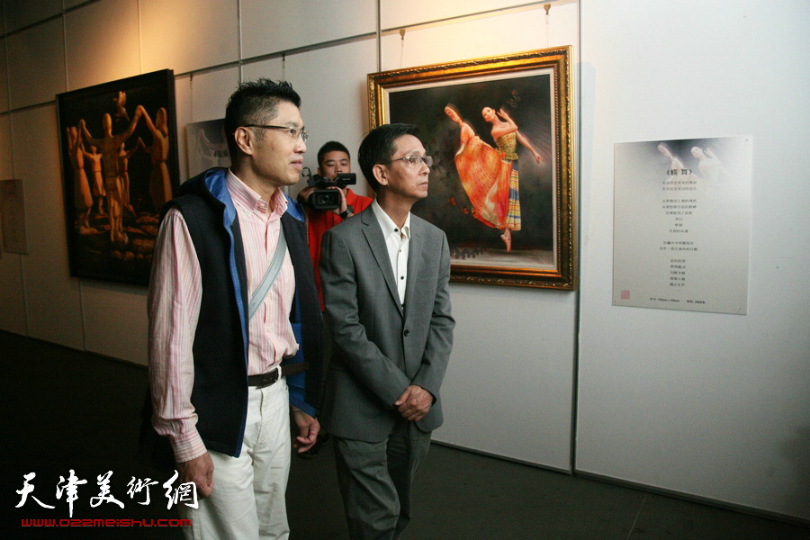 图为程亚杰与何家英在展览现场观摩画作。
