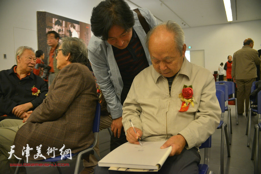 关维兴为观众在当日首发的《王双成水彩艺术》画册签字。