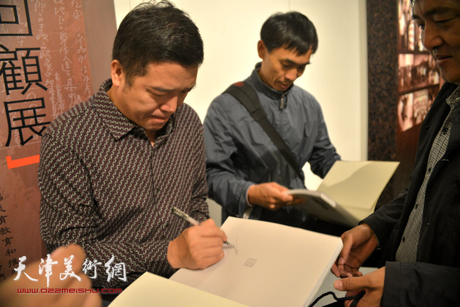 董克诚为观众在当日首发的《王双成水彩艺术》画册签字。