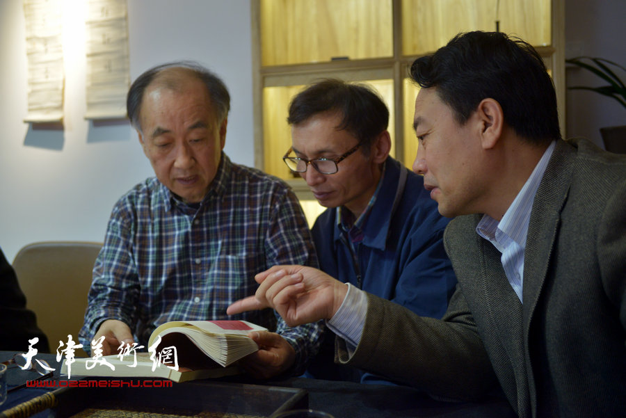 李建华、刘跃进、刘俊坡在首发式上观看民国出版的李叔同篆刻印蜕。